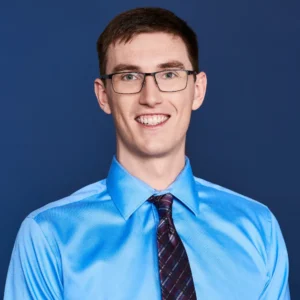 Smiling man in a blue dress shirt with polished corporate makeup, styled by Waring Makeup, Ottawa Corporate Makeup Artist.