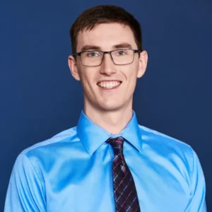 Smiling man in a blue dress shirt with polished corporate makeup, styled by Waring Makeup, Ottawa Corporate Makeup Artist.