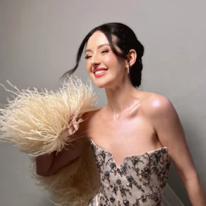 Joyful bride in beaded gown with classic makeup by Waring Makeup, Ottawa Wedding Makeup Artist, holding feather accents.